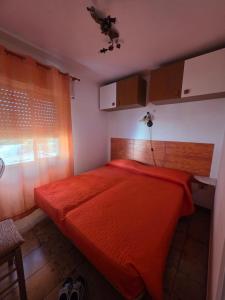 a bedroom with a bed with an orange bedspread at La casa di Claudia Torre Suda in Torre Suda