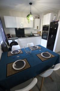 a kitchen with a table with chairs and a blue table cloth at T2 moderne, Parking, Proche Valence & Autoroute in Bourg-lès-Valence