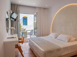 a bedroom with a bed and a balcony with a table at Galini Rooms in Naousa