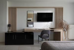 a bedroom with a desk and a tv on a wall at Suite Home in Anthoúsa +16 photos