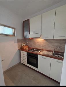 a kitchen with white cabinets and a stove top oven at La casa di Claudia Torre Suda in Torre Suda