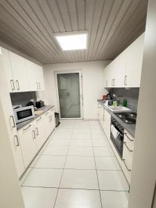 a kitchen with white cabinets and a ceiling at Private Apartment centrally located in Grafenwöhr