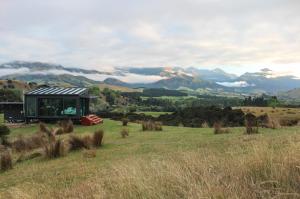 a house in a field with mountains in the background at Manakau PurePod in Kaikoura