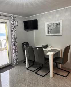 a dining room with a table and chairs and a television at Matea in Plomin