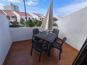 a table and chairs on a balcony with an umbrella at Garden City apartment Costa Adeje in Costa de Adeje