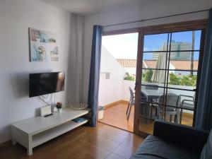a living room with a couch and a television and a balcony at Garden City apartment Costa Adeje in Costa de Adeje