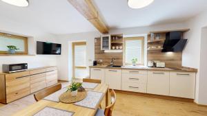 a kitchen with white cabinets and a table and chairs at Apartmány Nová Oleška in Huntířov +18 photos