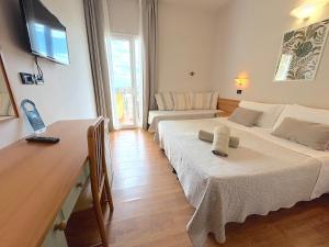 a room with two beds and a table and a couch at Hotel President in Cattolica
