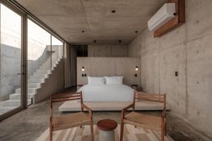 a bedroom with a bed and two chairs at Casa Talá by Lumina in Puerto Escondido
