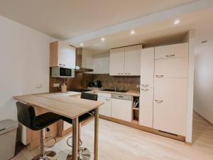 a kitchen with white cabinets and a wooden table at Chez Dubuiss in Houffalize
