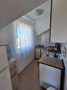 a small kitchen with a stove and a window at Mara apartman in Košljun