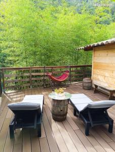 a deck with a hammock and a table and chairs at Chalet de la Grave in LʼEscarène