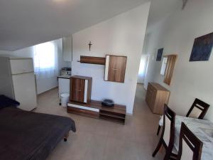 a room with a bed and a kitchen with a cross on the wall at Mara apartman in Košljun