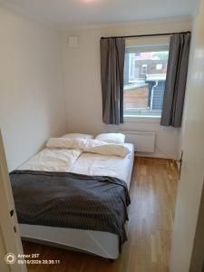 a small bedroom with a bed and a window at Sentrumsnær leilighet in Trondheim