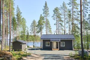 a tiny house in a forest with a lake at Villa Mustikkaranta Koli, oma ranta in Kolinkylä