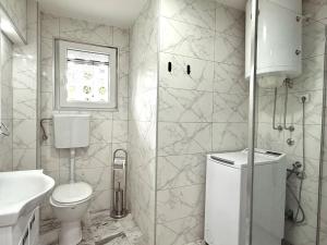 a white bathroom with a toilet and a sink at Apartman Stankovic in Negotin +9 photos