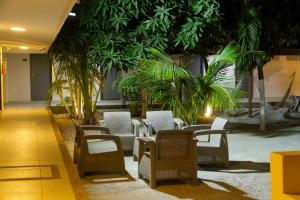 a room with chairs and tables and palm trees at Hotel Rodadero Beach Blue in Santa Marta