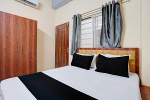 a bedroom with a large white bed with black pillows at Hotel O Peace Inn in Bhopal