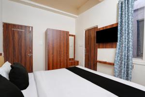a bedroom with a white bed and a wooden cabinet at Hotel O Peace Inn in Bhopal