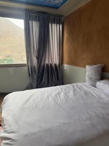 a bedroom with a white bed and a window at Berber lodge amssouzart in Tizgui +4 photos