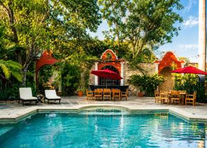 a pool with tables and chairs and umbrellas at Villa Merida Luxury Mansion - Adults Only Boutique Hotel in Mérida
