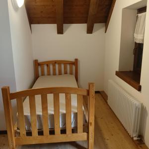 a bedroom with a wooden bed in a room at Stanza Cuori Malga Ciauta in Villanova