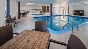 a swimming pool with a table and chairs and a table and a tablektopktop at Charlevoix Inn & Suites SureStay Collection by Best Western in Charlevoix