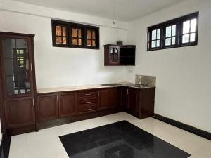 an empty kitchen with wooden cabinets and windows at Ceylander Suites in Kandy