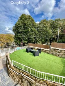 a grassy yard with two couches and a fence at Cosyholy in Vitry-sur-Seine