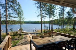 a porch with a wooden table and chairs and a lake at Villa Rantakukka Koli, oma ranta in Kolinkylä