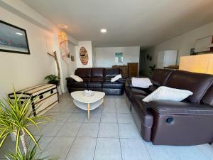 a living room with leather couches and a table at Pays Basque Ciboure - calme, port & plages à pied in Ciboure