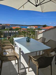 a white table and chairs on a balcony with an umbrella at Villa Castelana in Barbat na Rabu