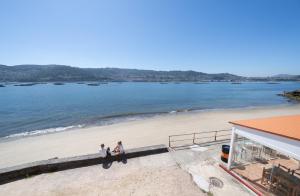 a group of three people walking on the beach at Apartamentos turísticos O Estaleiro in Moaña