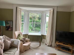 a living room with a couch and a large window at Watercombe House in Wheddon Cross
