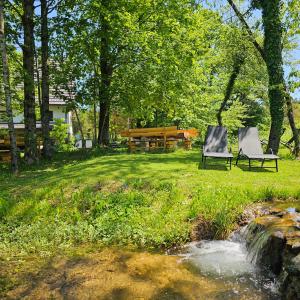 two chairs sitting in the grass next to a stream at Plitvice Streaming in Prijeboj