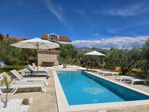 a pool with chairs and umbrellas next to a house at Villa Castelana in Barbat na Rabu