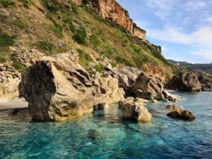 a body of water next to a mountain with rocks at La casa del Borgo in Cetraro +9 photos