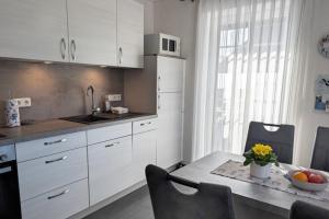 a kitchen with white cabinets and a table with a bowl of fruit at Dümmernest in Hüde