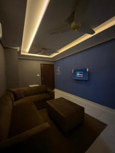 a living room with a couch and a tv on a blue wall at Maison Eleve Residency in Lahore +4 photos