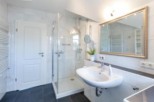 a bathroom with a sink and a shower and a mirror at Am Horizont 1 lichtdurchflutet modern zentral und ruhig Nähe Strand WLAN und Parkplatz inklusiv in Zingst +30 photos