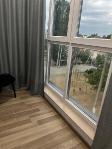 a room with two windows and a wooden floor at Apartament modern cu dormitor separat si balcon panoramic in Căuşeni