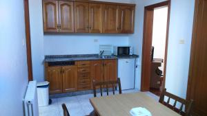 a kitchen with wooden cabinets and a table and a microwave at Apartamento Planeta 2º Dcha in O Porto de Espasante