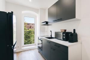 a kitchen with a sink and a microwave and a window at Altmarkt Palais in Löbau