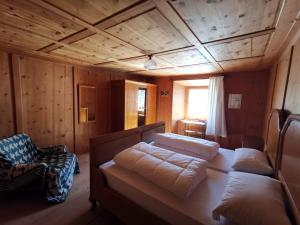 a room with a bed and a chair in a cabin at Im Laret, Lavin in Zernez
