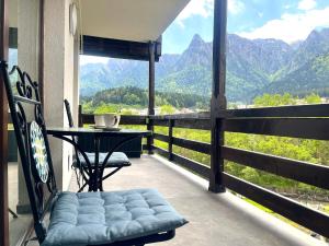 a balcony with a table and a chair and mountains at Mountain Stream Serenity - AC and Free Parking in Buşteni