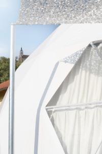 a white canopy with a building in the background at Glamping-Steiermark in Pöllauberg
