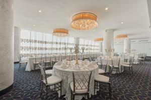a banquet room with white tables and chairs and chandeliers at Grand Tuscany Hotel in Houston