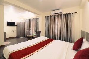a bedroom with a large white bed and a living room at Hotel Pun Inn Kathmandu in Kathmandu