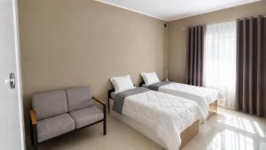 a bedroom with two beds and a chair at Milestone Villa in Antananarivo +5 photos