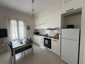 a white kitchen with a table and a white refrigerator at The Mulberry House Heritage by the Sea in Alexandroupoli